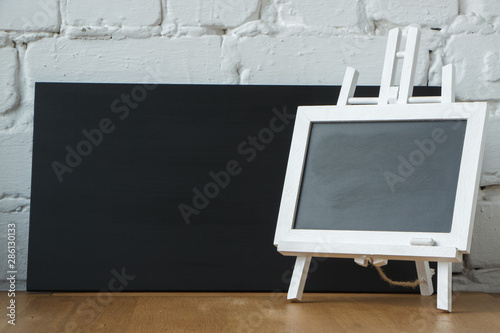 Close-up of a miniature chalk board on the background of a large black chalk board, selective focus