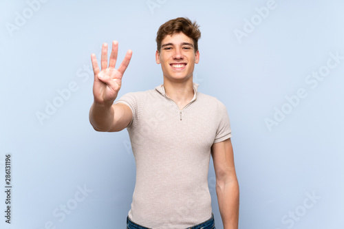 Handsome young man over isolated blue wall happy and counting four with fingers