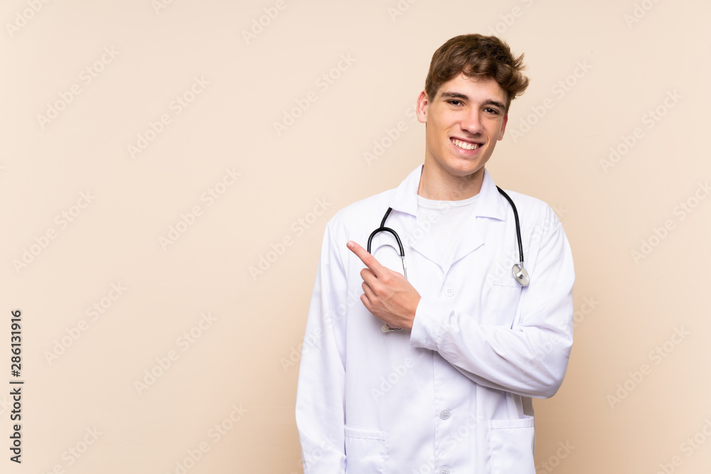 Handsome doctor young man over isolated wall pointing to the side to present a product Handsome doctor young man over isolated wall pointing to the side to present a product