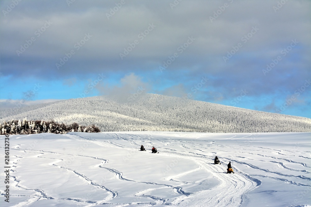 people driving snowmobiles on a snowy field