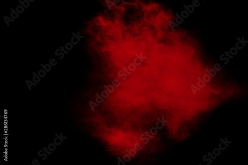 Red color powder explosion on black background.Freeze motion of red dust particles splashing.
