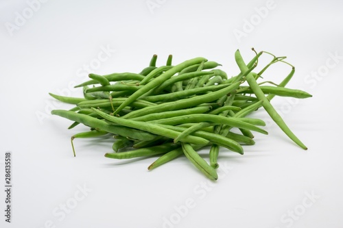 A handful of green beans fresh from the market in front of white background