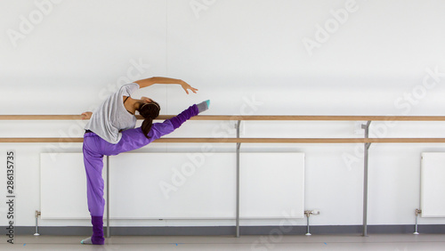 young ballerina stretching at ballet barre
