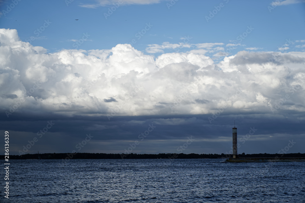 Storm cloud and lighthouse. Dramatic cloudscape texture. Dark heavy thunderstorm clouds before rain. Overcast rainy bad weather. Storm warning. Natural blue background of cumulonimbus