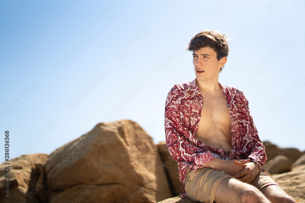 young man with short and flower shirt among rocks