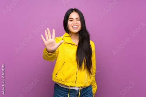 Young teenager Asian girl over isolated purple background counting five with fingers