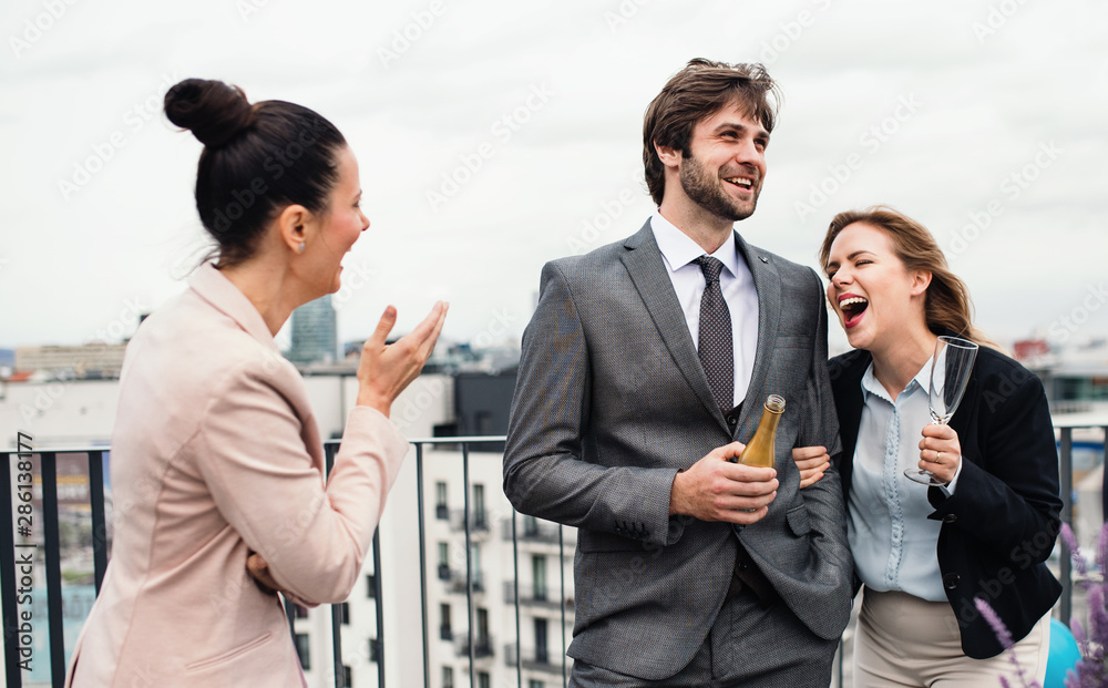 A group of joyful businesspeople having a party outdoors on roof terrace in city. A group of joyful businesspeople having a party outdoors on roof terrace in city.