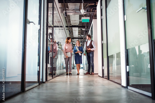 Foto Group of business people walking in an office building, talking.