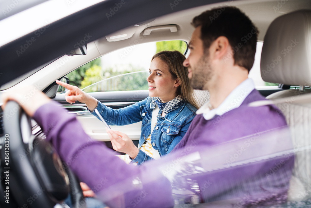 Happy young couple with smartphone sitting in car, talking. Happy young couple with smartphone sitting in car, talking.