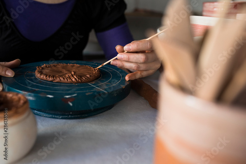 Potter marking clay base with wooden tool photo