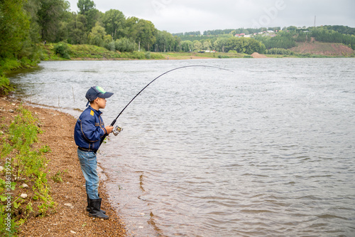 a boy with a fishing rod pulls a fish