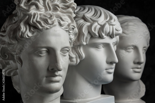 Gypsum copy of ancient statue Apollo, Antinous and Venus head on dark textured background. Plaster sculpture face.