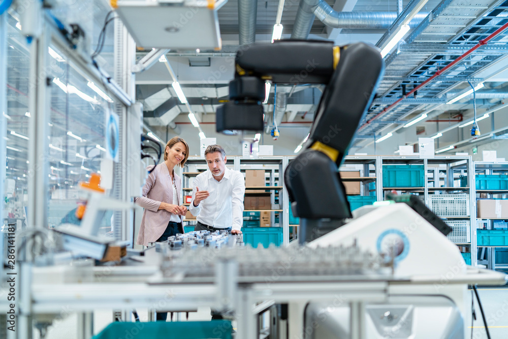 Businessman and businesswoman talking in a modern factory hall Businessman and businesswoman talking in a modern factory hall