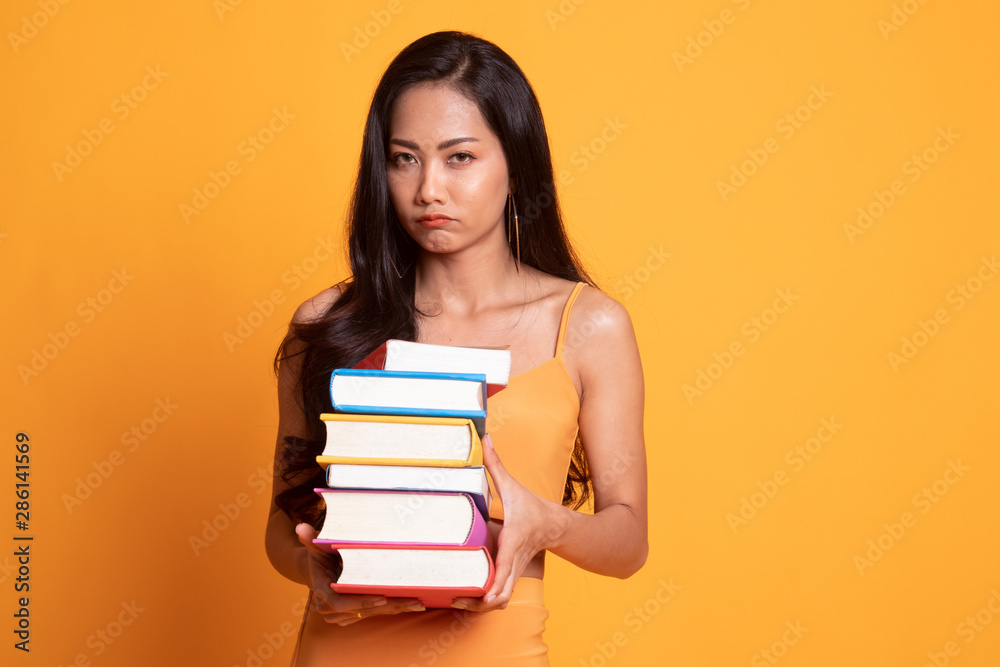 Unhappy young Asian woman studying with may books. Unhappy young Asian woman studying with may books.