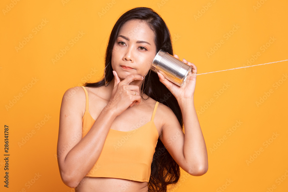 Young Asian woman hearing with tin can phone and thinking. Young Asian woman hearing with tin can phone and thinking.