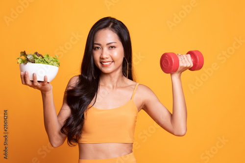 Healthy Asian woman with dumbbells and salad.