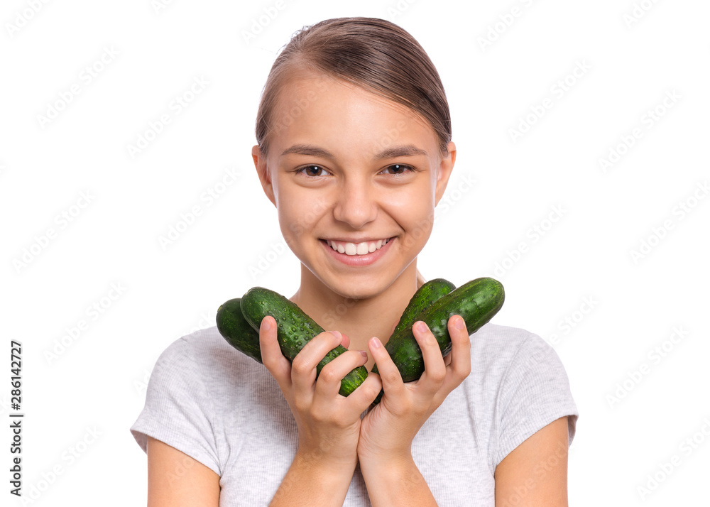 Portrait of beautiful young teen girl holding fresh green cucumbers, isolated on white background. Smiling pretty child with healthy raw vegetables in hands. Organic natural healthy food produce. Portrait of beautiful young teen girl holding fresh green cucumbers, isolated on white background. Smiling pretty child with healthy raw vegetables in hands. Organic natural healthy food produce.