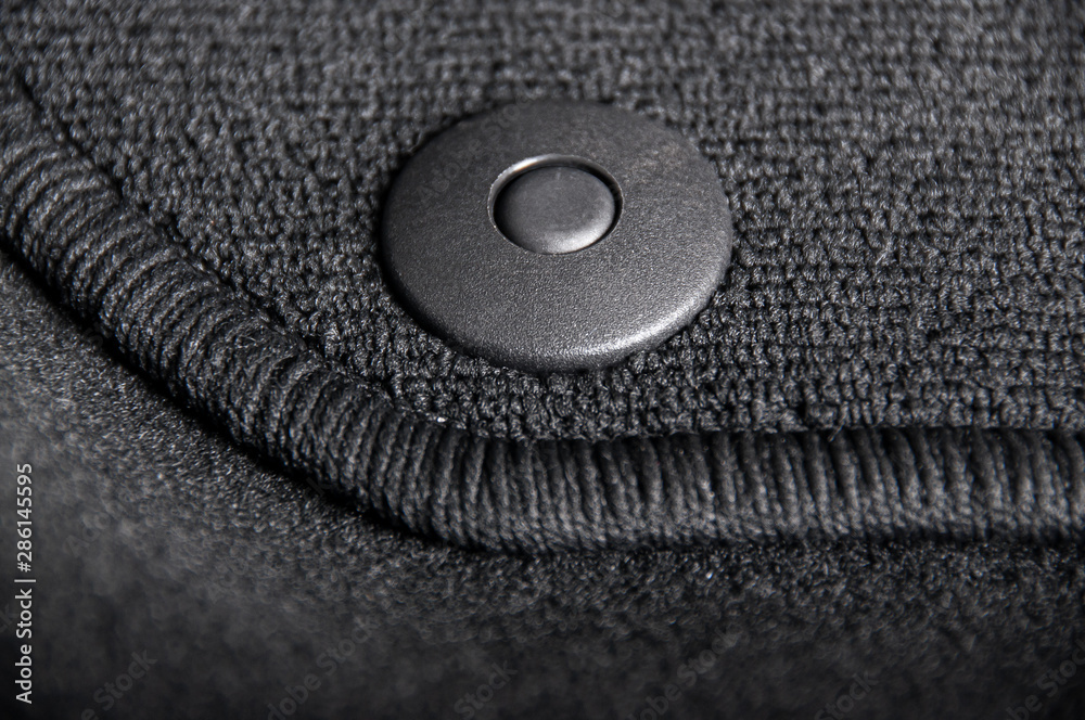 Black textile car mat with floor holders in black auto interior Black textile car mat with floor holders in black auto interior