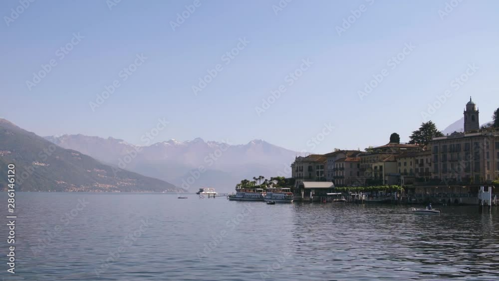 Ferry boats on water by pier lakeside town of Bellagio on Como lake in Lombardy Italy, view of city harbor on beautiful mountain lake. Early morning sunny day Ferry boats on water by pier lakeside town of Bellagio on Como lake in Lombardy Italy, view of city harbor on beautiful mountain lake. Early morning sunny day