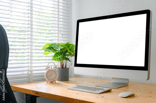 workspace with computer with blank white screen, and office supplies on a wooden desk © escapejaja