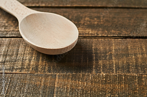 Single clean wooden spoon lies on old brown rustic wooden planks. Space for text