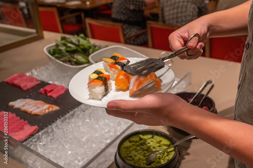 Man choosing delicious sushi in luxury buffet restaurant