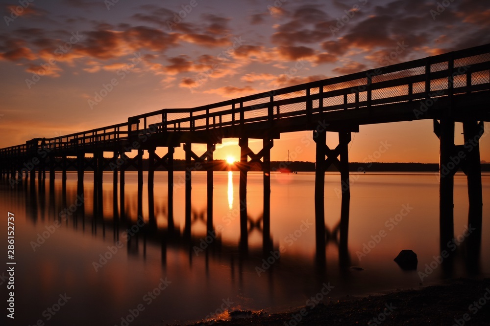 Bridge reflected in sea against cloudy sky during sunset Bridge reflected in sea against cloudy sky during sunset