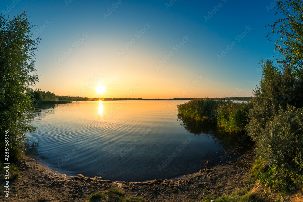 Romantic summer sunset behind a calm lake Romantic summer sunset behind a calm lake