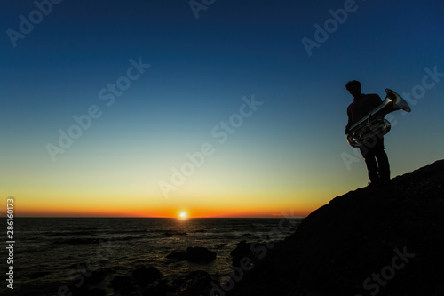 Silhouette of musician on the Sea beach during sunset.