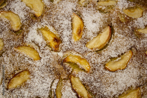 View of a freshly baked apple pie sprinkled with icing sugar, with apple slices