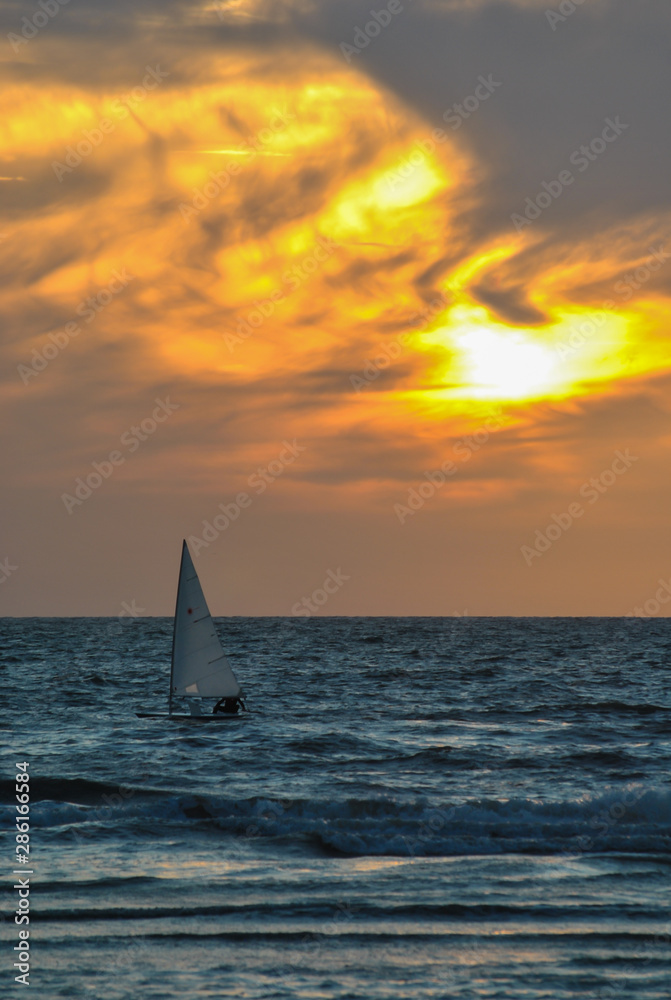 Sailboat from the evening beach at sunset time