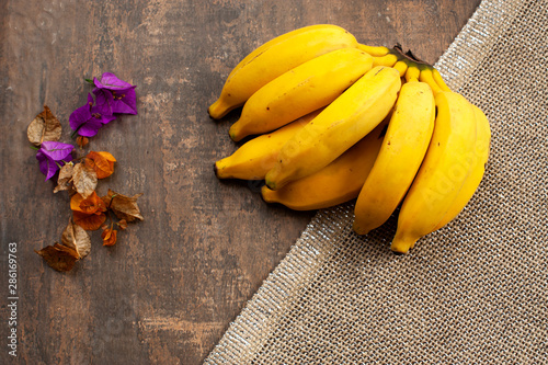 Bananas, healthy fruit on aged wood table background.Dried, colorful flowers beside, decorating. photo