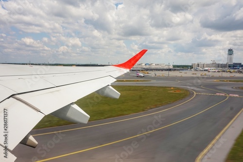 The wing of a take-off airplane. Below is the airport.