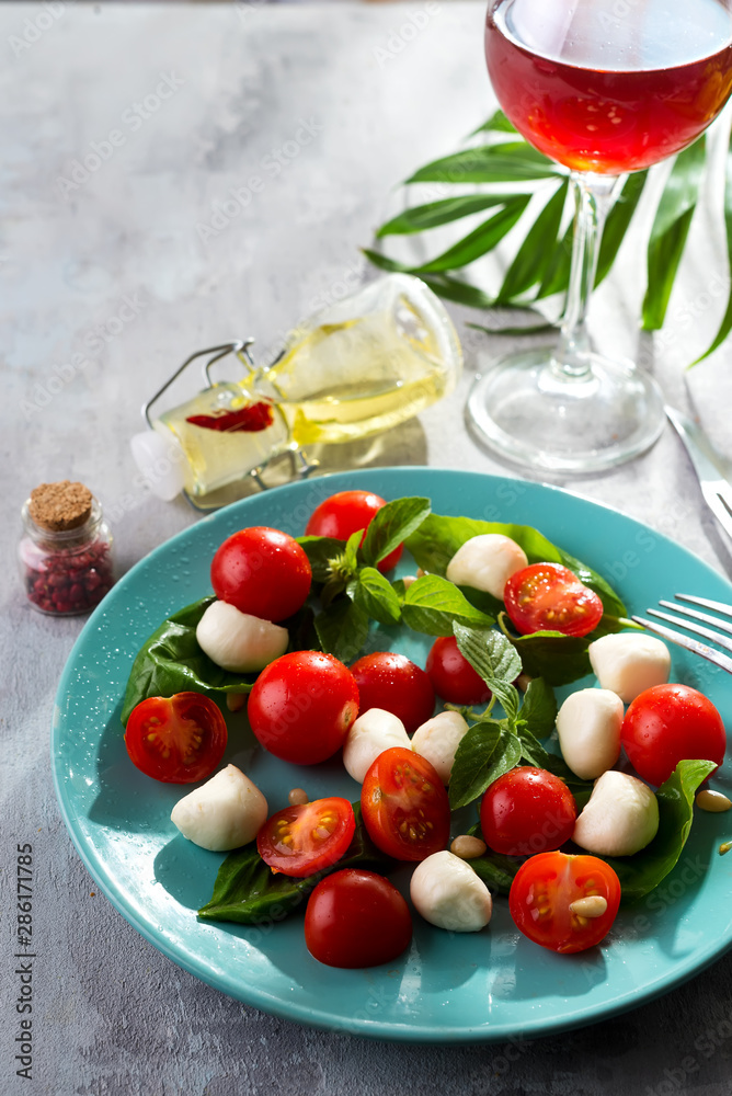 Italian Caprese salad with red tomatoes, fresh organic mozzarella and basil on stone table, Top view