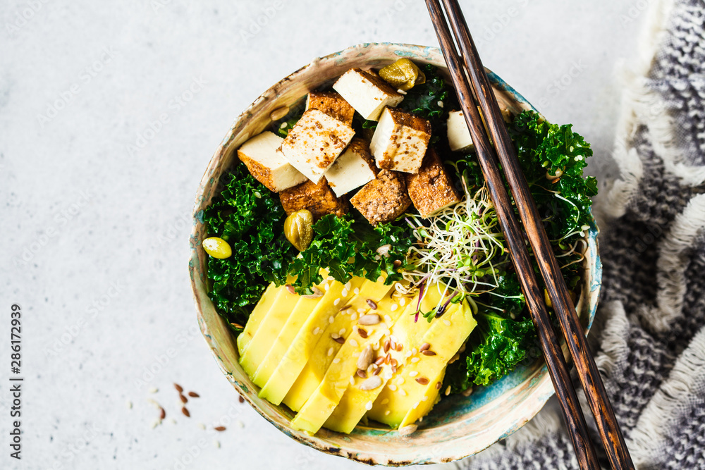 Vegan salad with smoked tofu, kale, avocado and sprouts in bowl. Vegan salad with smoked tofu, kale, avocado and sprouts in bowl.