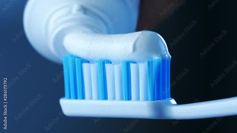 Dental Health - Squeezing white toothpaste from a tube onto a toothbrush. Dental Health - Squeezing white toothpaste from a tube onto a toothbrush.