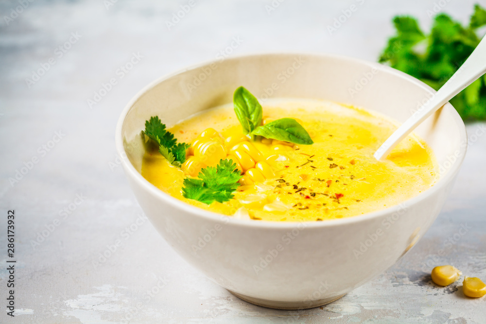Vegan corn cream soup in white bowl on a gray background. Vegan corn cream soup in white bowl on a gray background.
