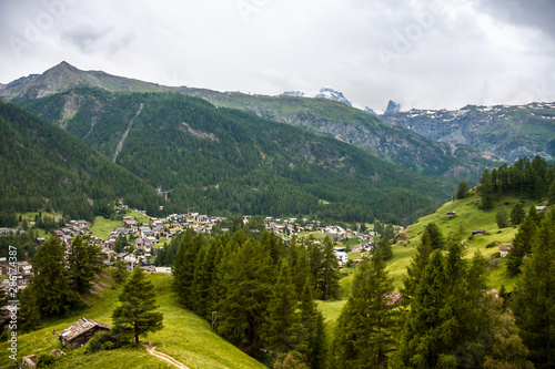 View of resort Zermatt on Alpine valley landscape, mountain, green meadow, coniferous forest.