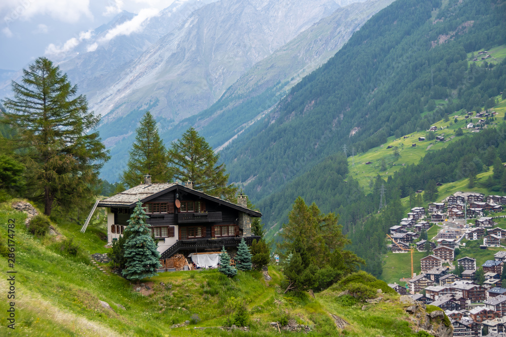 Spectacular summer alpine landscape, mountain swiss wooden chalet with high mountains in background, Zermatt, Switzerland