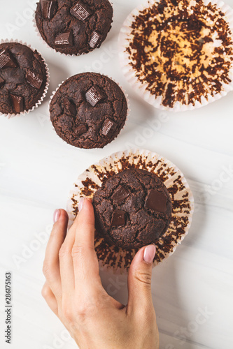 Chocolate vegan muffin in hand  on white background.