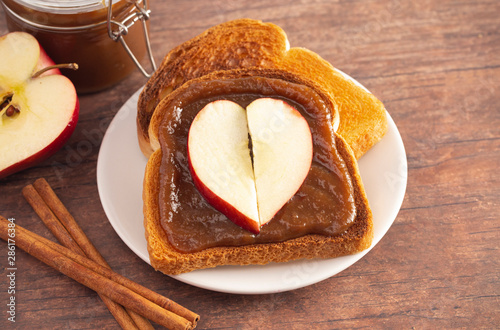 A Slice of Toast with Apple Butter and a Heart Shaped Apple on a Wooden Table