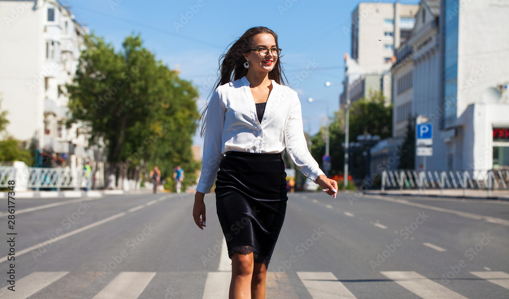 Young happy brunette woman in black skirt and white blouse