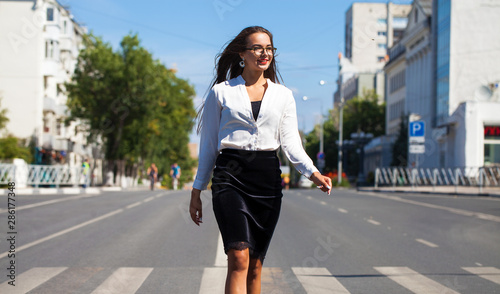 Young happy brunette woman in black skirt and white blouse