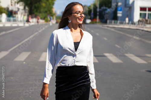 Young happy brunette woman in black skirt and white blouse © Andrey_Arkusha