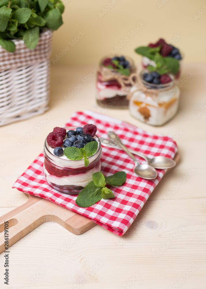 Raspberry cakes in glass jar with fresh fruit and cream cheese on a red napkin. Raspberry cakes in glass jar with fresh fruit and cream cheese on a red napkin.
