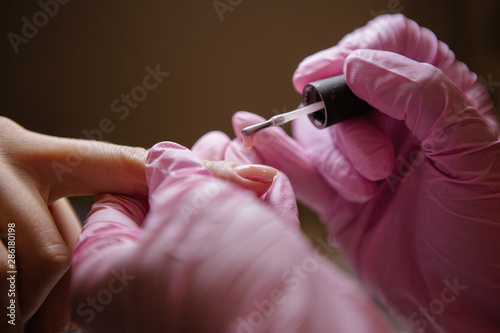 Woman in salon receiving manicure by nail beautician