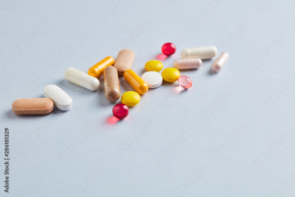 Multicolor vitamins and supplements on bright paper background. Concept for a healthy dietary supplementation. Copy space. Multicolor vitamins and supplements on bright paper background. Concept for a healthy dietary supplementation. Copy space.