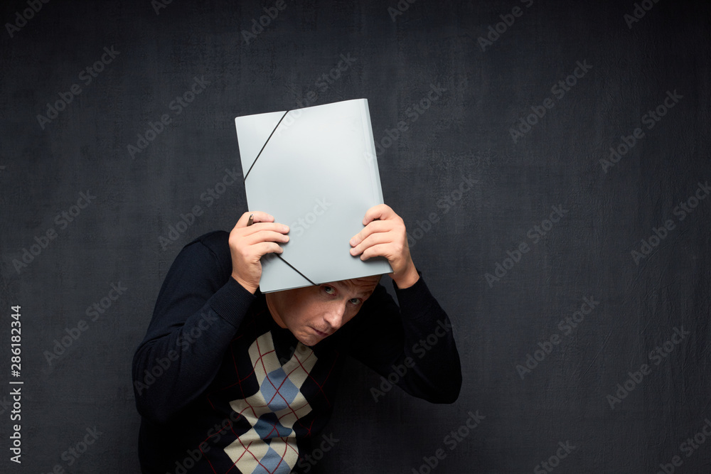 Naklejka premium Portrait of frightened man peeping from under folder