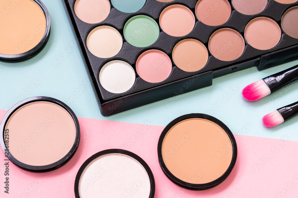 Powder and blush on a pastel blue and pink background.Trendy palette of eyeshadow. Cosmetic. Beauty products. Makeup brushes. Powder and blush on a pastel blue and pink background.Trendy palette of eyeshadow. Cosmetic. Beauty products. Makeup brushes.