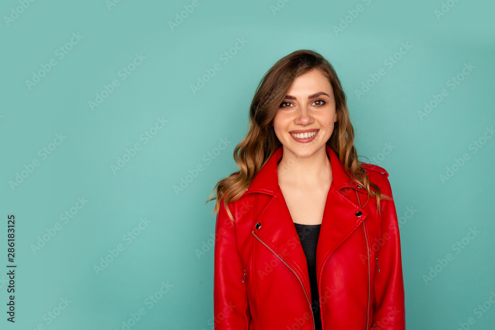 Portrait of smiling young lady with white teeth standing in a studio isolated over the blue background Portrait of smiling young lady with white teeth standing in a studio isolated over the blue background